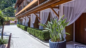 A wooden building with a balcony, a paved walkway, and potted plants. - Pousada Vila Barequeçaba (São Sebastião)