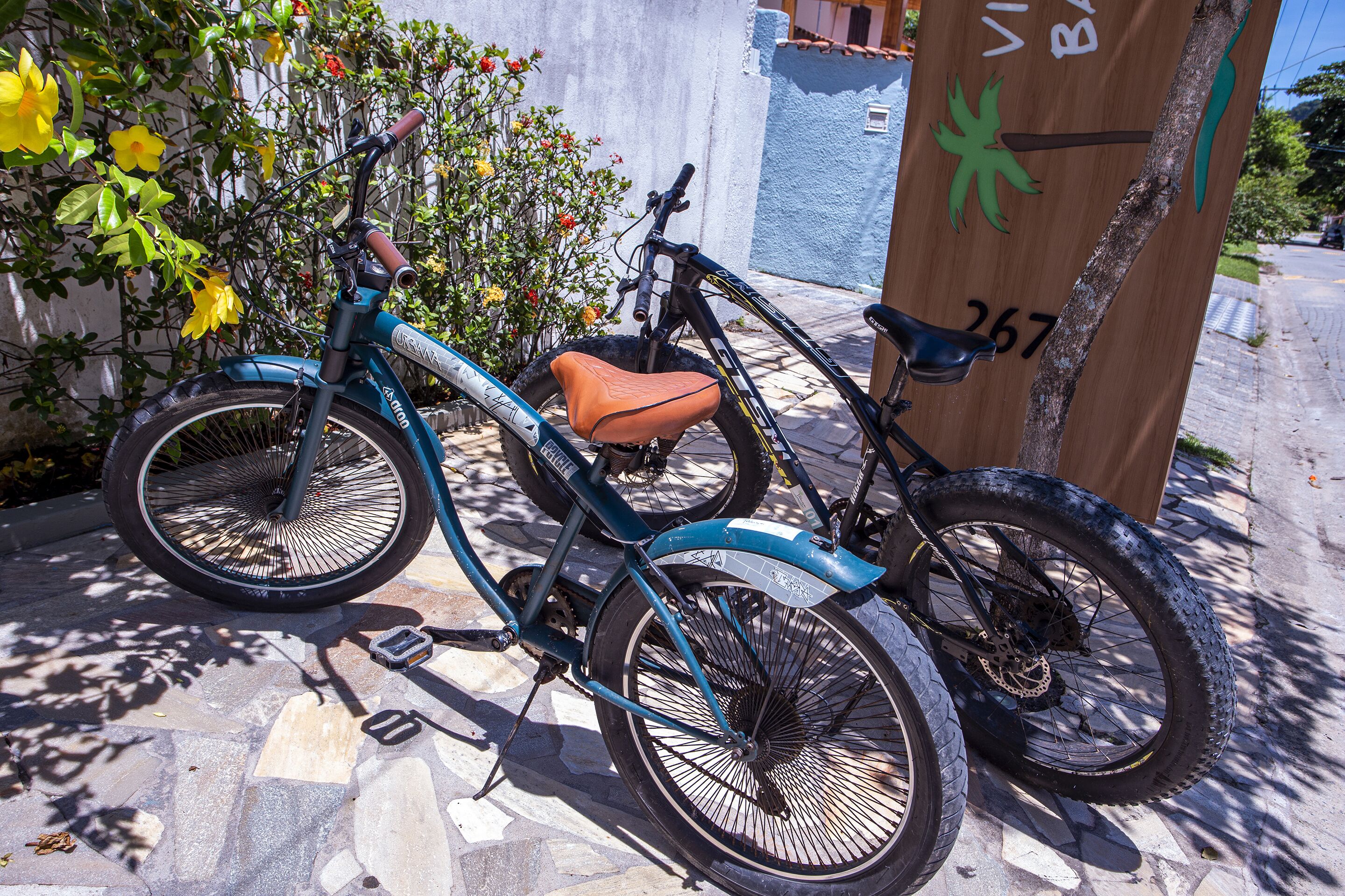 A teal bicycle with a brown seat parked next to a wooden post with graffiti.