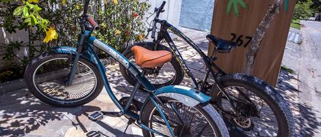 A teal bicycle with a brown seat parked next to a wooden post with graffiti.