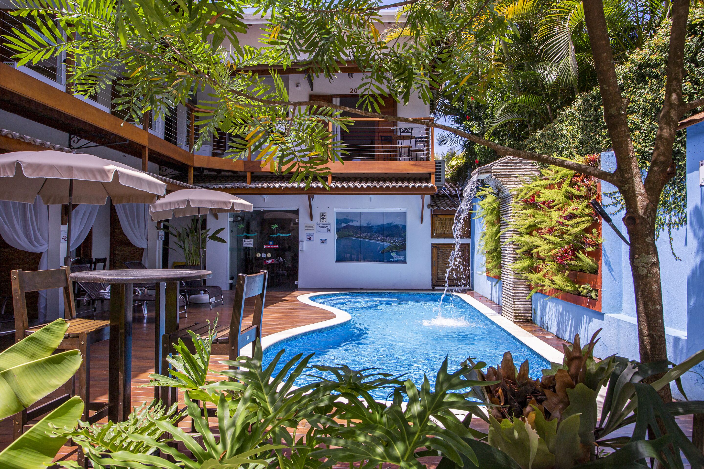 A pool area with a wooden deck, outdoor seating, and a water feature.