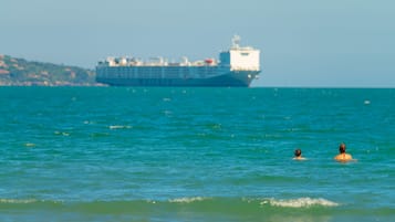 Un gran barco en el océano con dos personas nadando en el agua.