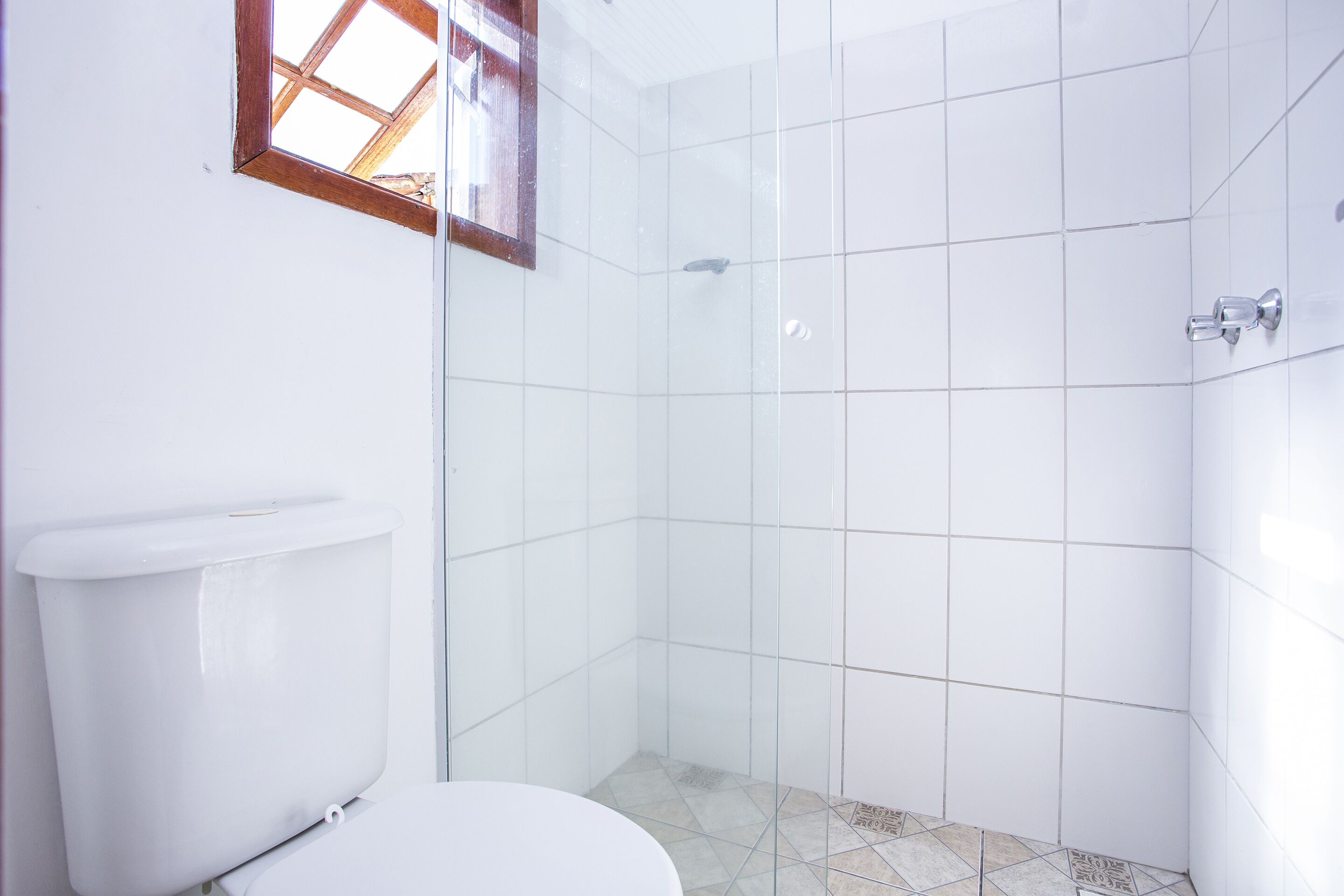 Un baño con inodoro, cabina de ducha y ventana.