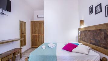 Une chambre à coucher comprenant un lit, une tête de lit en bois, une table de chevet, un banc, une télévision et une armoire.