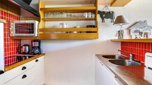 Une cuisine compacte équipée d’un four à micro-ondes encastré, d’une machine à café et d’un évier.