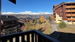 A mountain resort with snow-capped peaks in the background, a pedestrian path, and buildings with balconies. - Studio for 4 in Vallandry, near slopes (Peisey-Vallandry)