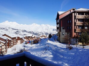 Une station de montagne enneigée, avec des bâtiments en bois et un télésiège.