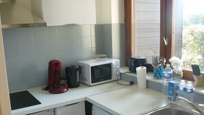 A compact kitchen with a dishwasher, washing machine, microwave, toaster, and coffee maker. - Nice T1 Bis ideally located, parking, wifi and garden (Thonon-les-Bains)