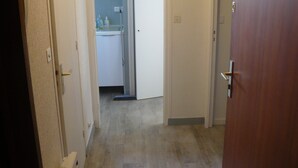 Un couloir menant à une salle de bain équipée d’un lavabo et d’un miroir.
