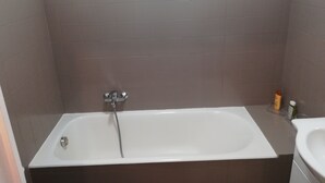A bathroom with a bathtub, a sink, and a showerhead. - Nice T1 Bis ideally located, parking, wifi and garden (Thonon-les-Bains)