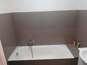 A bathroom with a bathtub, a sink, and a showerhead.