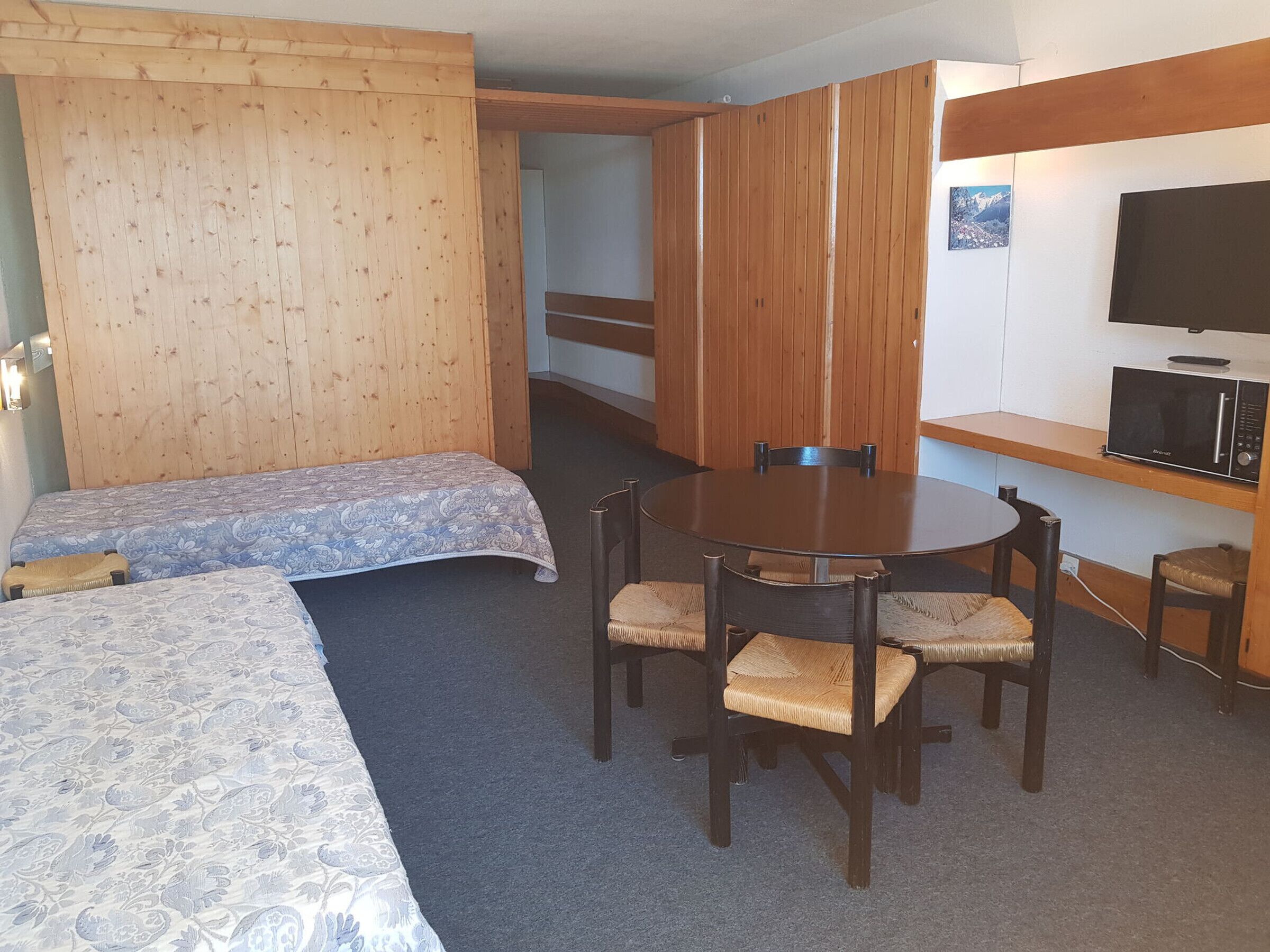 Una camera d'albergo con un letto, un tavolino rotondo con sedie, un forno a microonde e una televisione.