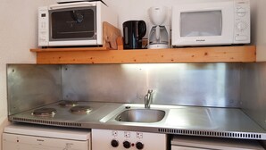 Une cuisine compacte équipée d’un four à micro-ondes, d’une machine à café et d’un évier.