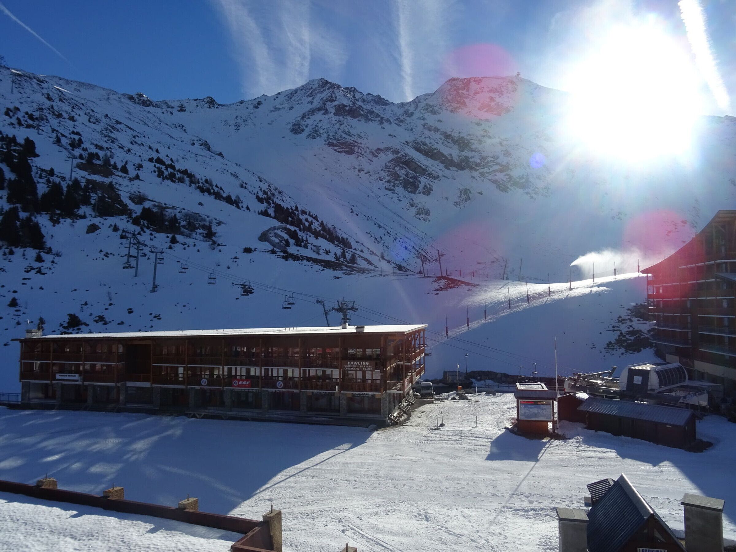 Ett snötäckt berg med en skidlift, en byggnad med flera våningar och en parkeringsplats.