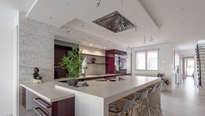 A modern kitchen with a central island, bar stools, and a large window. - 2 Bedroom Apartment 84m² Promenade des Anglais Last Floor sea View + Solarium (Nice)