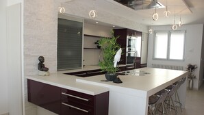 A modern kitchen with a central island, bar stools, and pendant lighting. - 2 Bedroom Apartment 84m² Promenade des Anglais Last Floor sea View + Solarium (Nice)