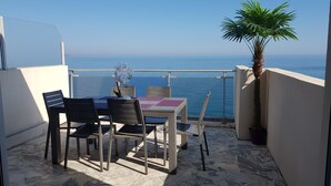 A balcony with a table and chairs, a potted plant, and a view of the sea. - 2 Bedroom Apartment 84m² Promenade des Anglais Last Floor sea View + Solarium (Nice)
