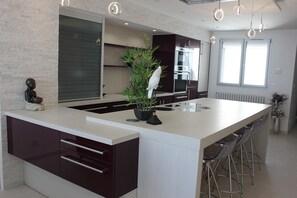Una cocina moderna con una isla central, taburetes de bar y una planta en maceta.