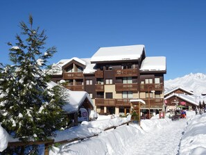 A multi-story building with balconies and a snow-covered roof, surrounded by snow. - Cozy apartment for 6 in Vallandry, near slopes and shops (Peisey-Vallandry)