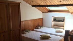 A room with two beds, wooden wardrobe, and a skylight. - Charming traditional home in the quiet groves. 10 minutes from beaches (Sartene)