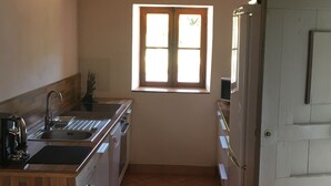 A compact kitchen with a washing machine, a sink, and a window with sunlight. - Charming traditional home in the quiet groves. 10 minutes from beaches (Sartene)
