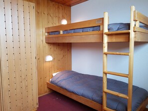 A bunk bed with a ladder, wooden walls, and two wall-mounted lights.