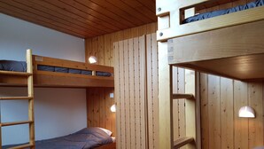 Camera con letto a castello, pareti in legno, una scala e un letto singolo.