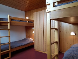 Ein Schlafraum mit Etagenbett, Holzwänden und einer Leiter.