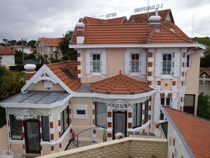 A multi-story building with a red-tiled roof, white-framed windows, and a balcony with a glass enclosure. -  studio for 2 people well equipped renovated, air-conditioned 3 stars (Arcachon)