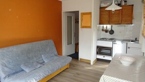 A compact living space with a sofa, kitchenette, and a small dining area.