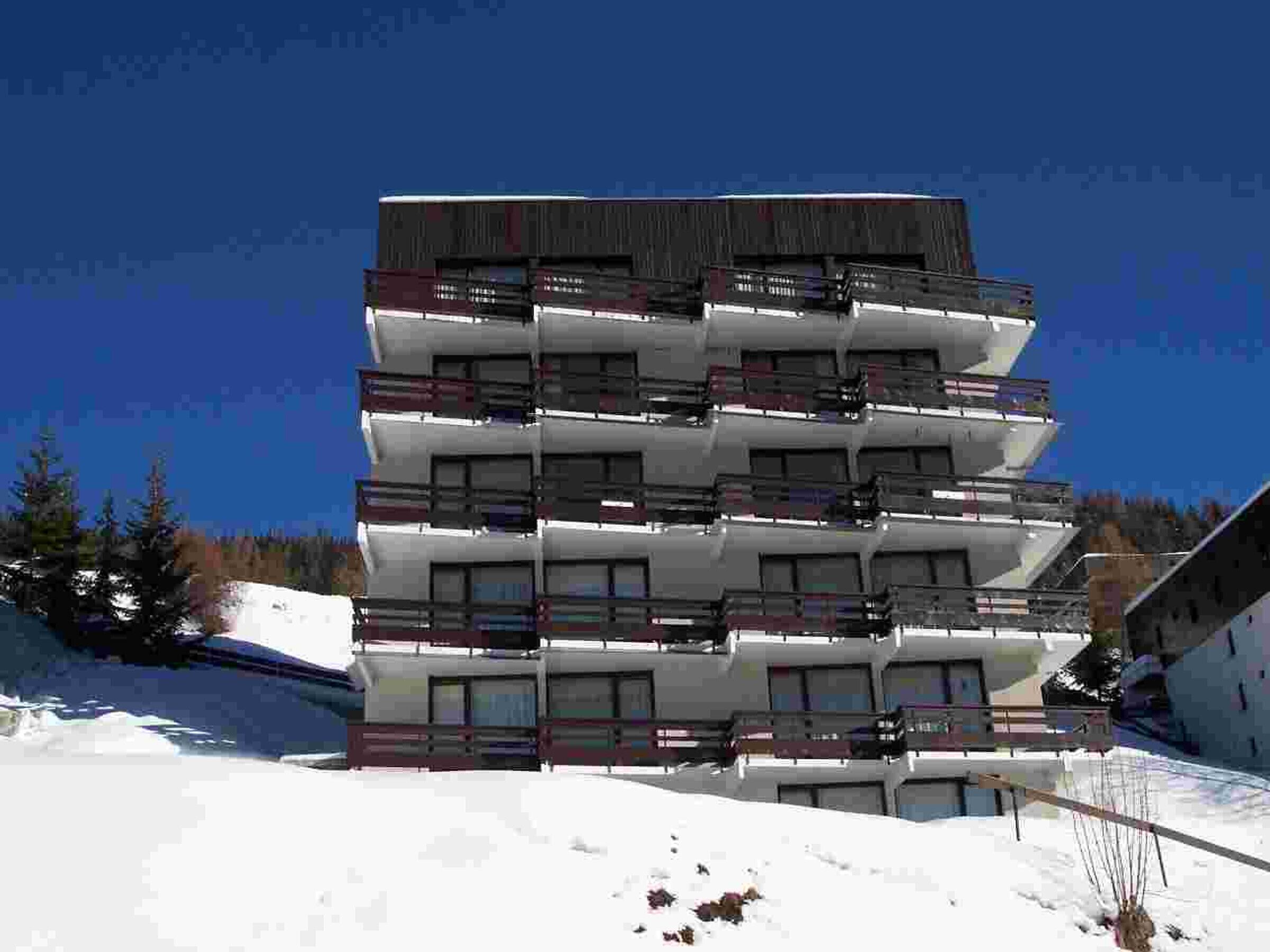 A multi-story building with balconies, likely a hotel or apartment complex, situated in a snowy area.