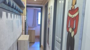 A hallway with a wooden floor, a rug, a door with a red figure, and a window with curtains. - Lovely apartment in Méribel center, close to slopes, for 5 persons (Méribel)