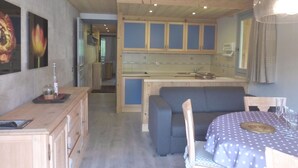 A compact kitchen with wooden cabinets and a central island, a dining area with a table and chairs, and a hallway leading to another room. - Lovely apartment in Méribel center, close to slopes, for 5 persons (Méribel)
