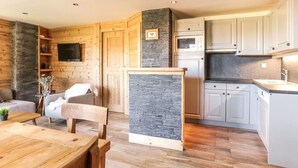 Una cocina moderna con armarios de madera, una pared de acento de piedra y una televisión empotrada.