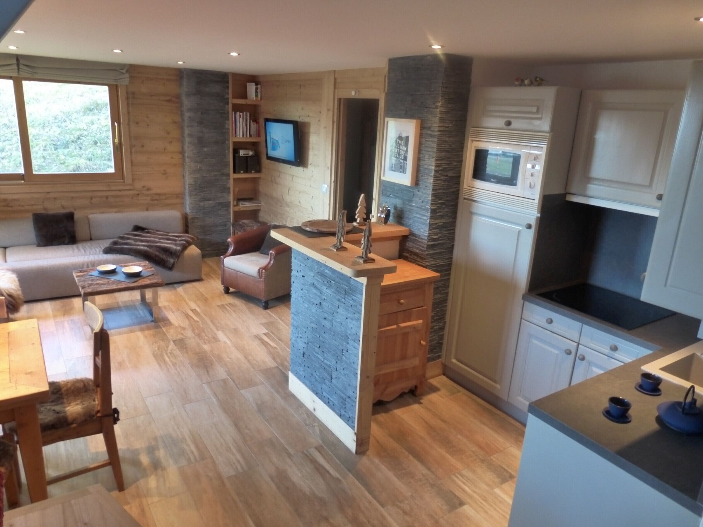A modern kitchen with a central island, wooden cabinets, and a built-in microwave.