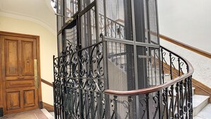 A spiral staircase with ornate metal railings and a wooden door at the base. - N&J - LAVINIA - Central - Close sea (Niza)