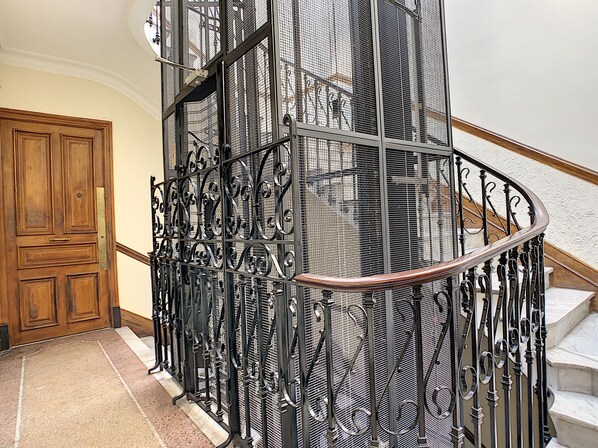 A spiral staircase with ornate metal railings and a wooden door at the base.