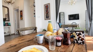 A dining area with a wooden table set for breakfast, including bread, a bottle of orange juice, and a candle. - N&J - LAVINIA - Central - Close sea (Niza)