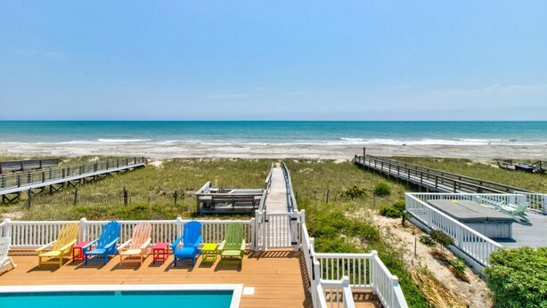 A beach view from a deck with colorful Adirondack chairs and a pool. - ☀️Dolphin Run: Oceanfront w/ Private Pool-Large Beachfront Deck-Pet Friendly☀️ (Kure Beach)
