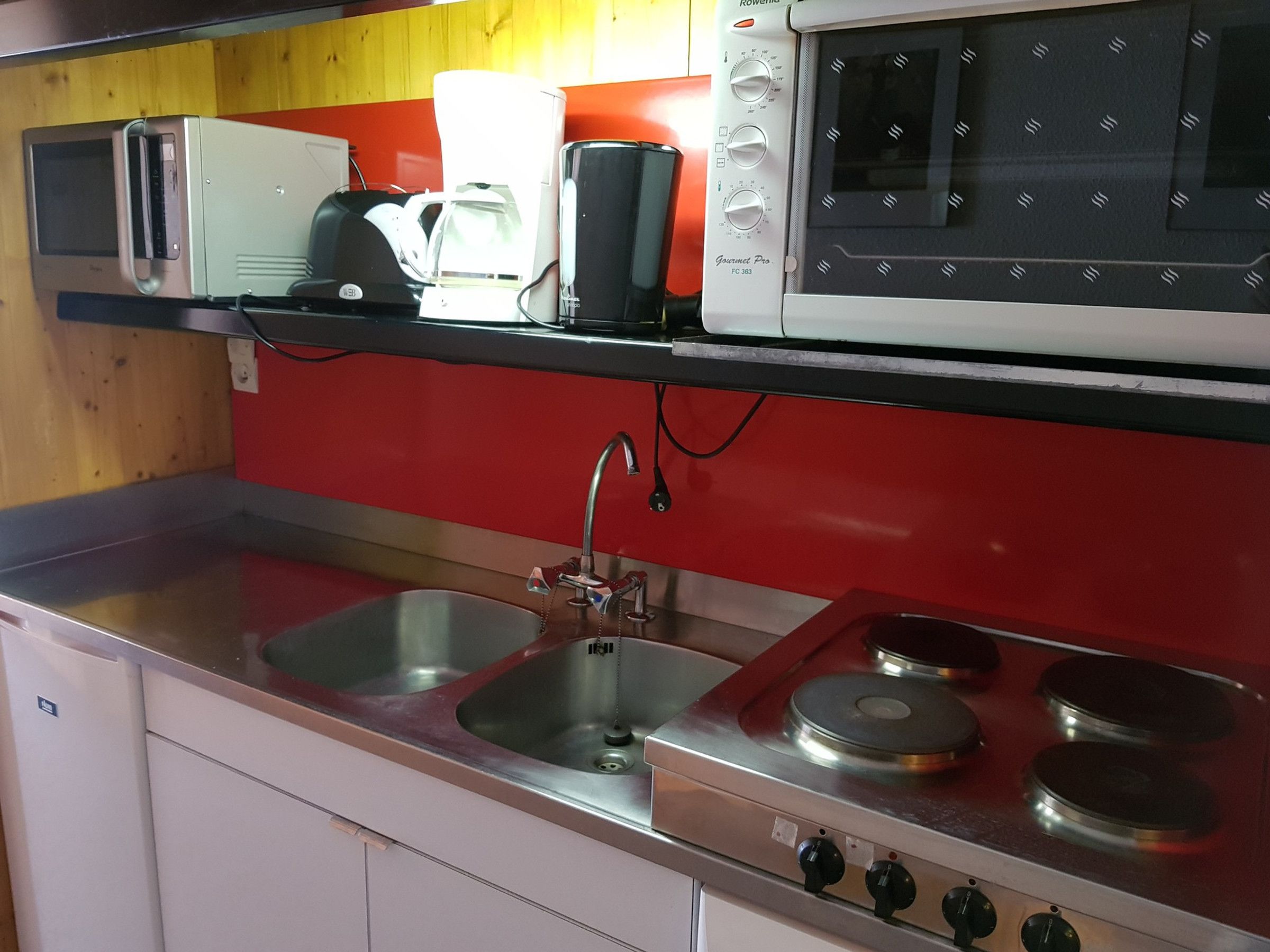 A compact kitchen with a microwave, coffee maker, and gas stove.