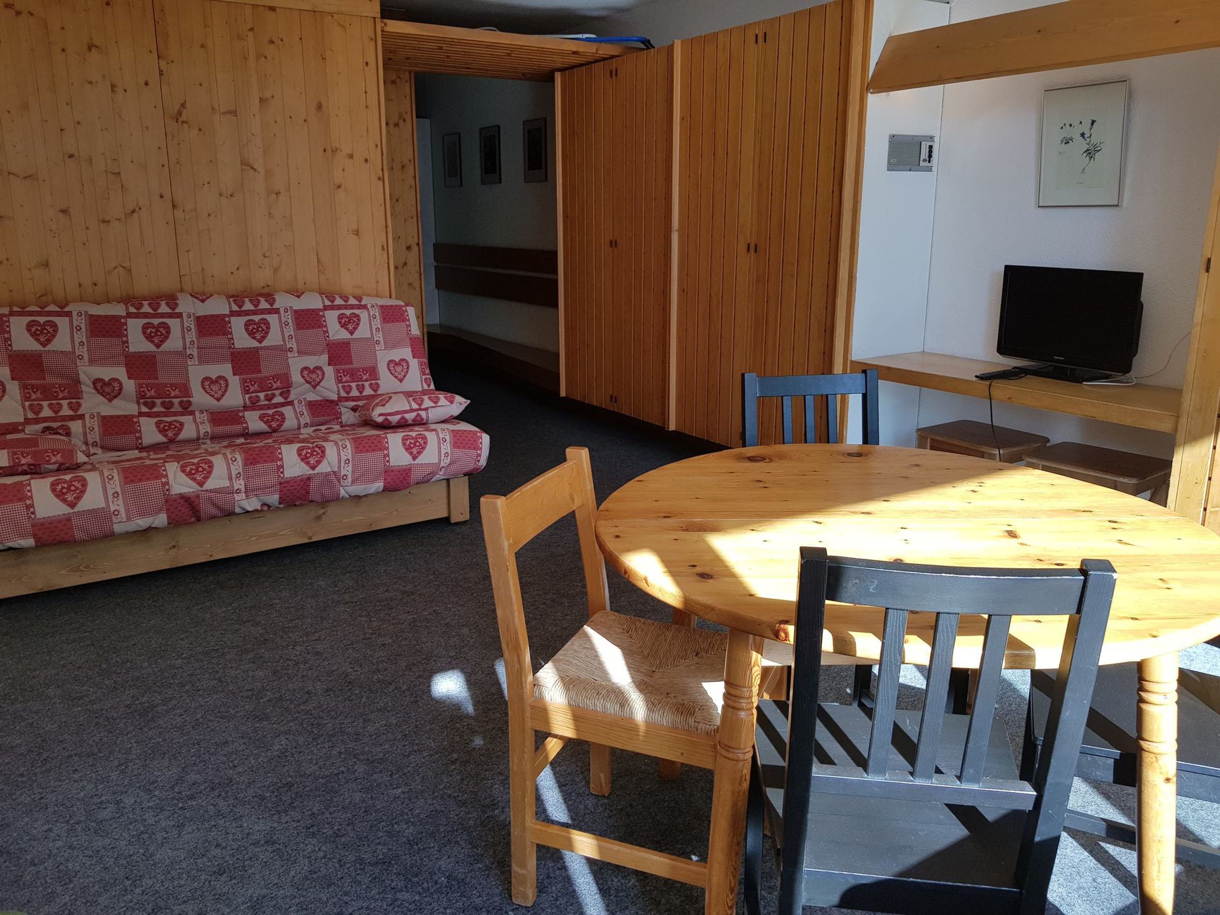 Une pièce chaleureuse avec un canapé en bois, une table ronde en bois et deux chaises.