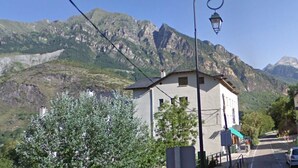 Uma aldeia montanhosa com edifícios de pedra, uma igreja e uma estrada que serpenteia até a montanha.