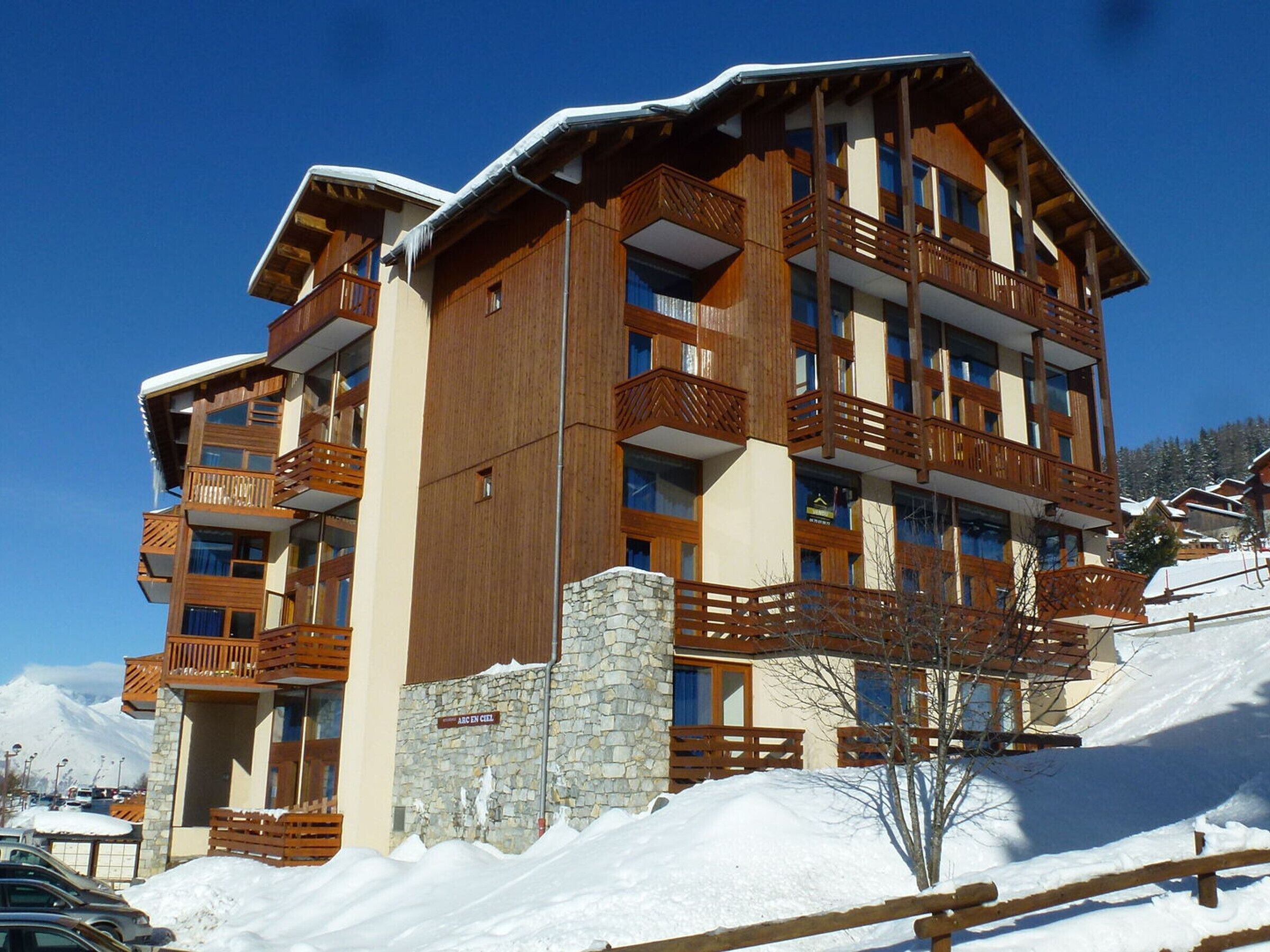 A multi-story hotel with wooden balconies and a stone facade.