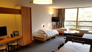 Une chambre d’hôtel comprenant un lit, un bureau avec un ordinateur, une télévision, un canapé et une table à manger.