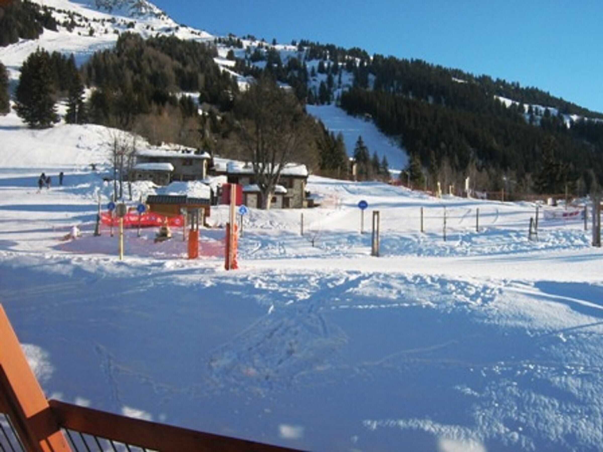 Ein schneebedecktes Skigebiet mit blauem Himmel, einer Seilbahn und einem Berg im Hintergrund.