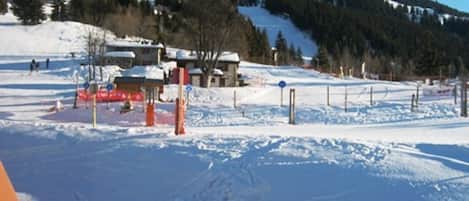 Ein schneebedecktes Skigebiet mit blauem Himmel, einer Seilbahn und einem Berg im Hintergrund.