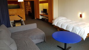 Une chambre d’hôtel avec un lit, un canapé, une petite table, un bureau et un ordinateur.