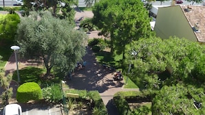 A parking area with a white car, surrounded by greenery and a pathway leading to a beach. - Balcony facing the sea, 3 rooms (76m2), private park DEPARTURE ON SATURDAY EXCLUSIVELY (Cagnes-Sur-Mer)