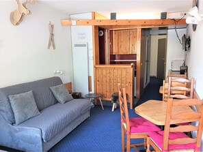 A compact living space with a sofa, a small table, and a dining area with wooden chairs. - Ski-in/ski-out studio for 4 at Arc 2000 (Les Arcs 2000)