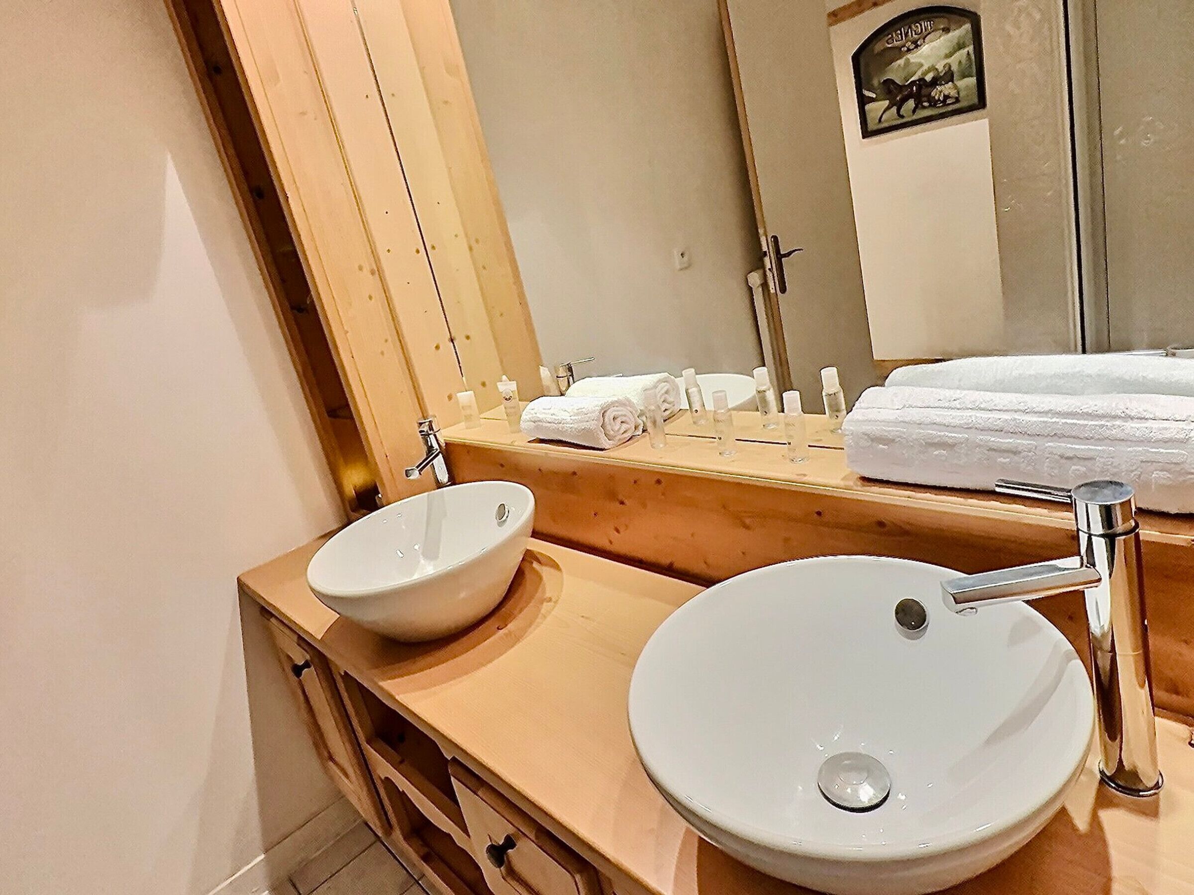Un baño con dos lavamanos blancos, tocador de madera y espejo con marco decorativo.