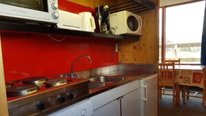 Une cuisine compacte équipée d’un lave-vaisselle blanc, d’une cuisinière à quatre brûleurs, d’un four à micro-ondes et d’une machine à café.